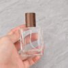 Hand Holding Square Glass Perfume Bottle Walnut Cap